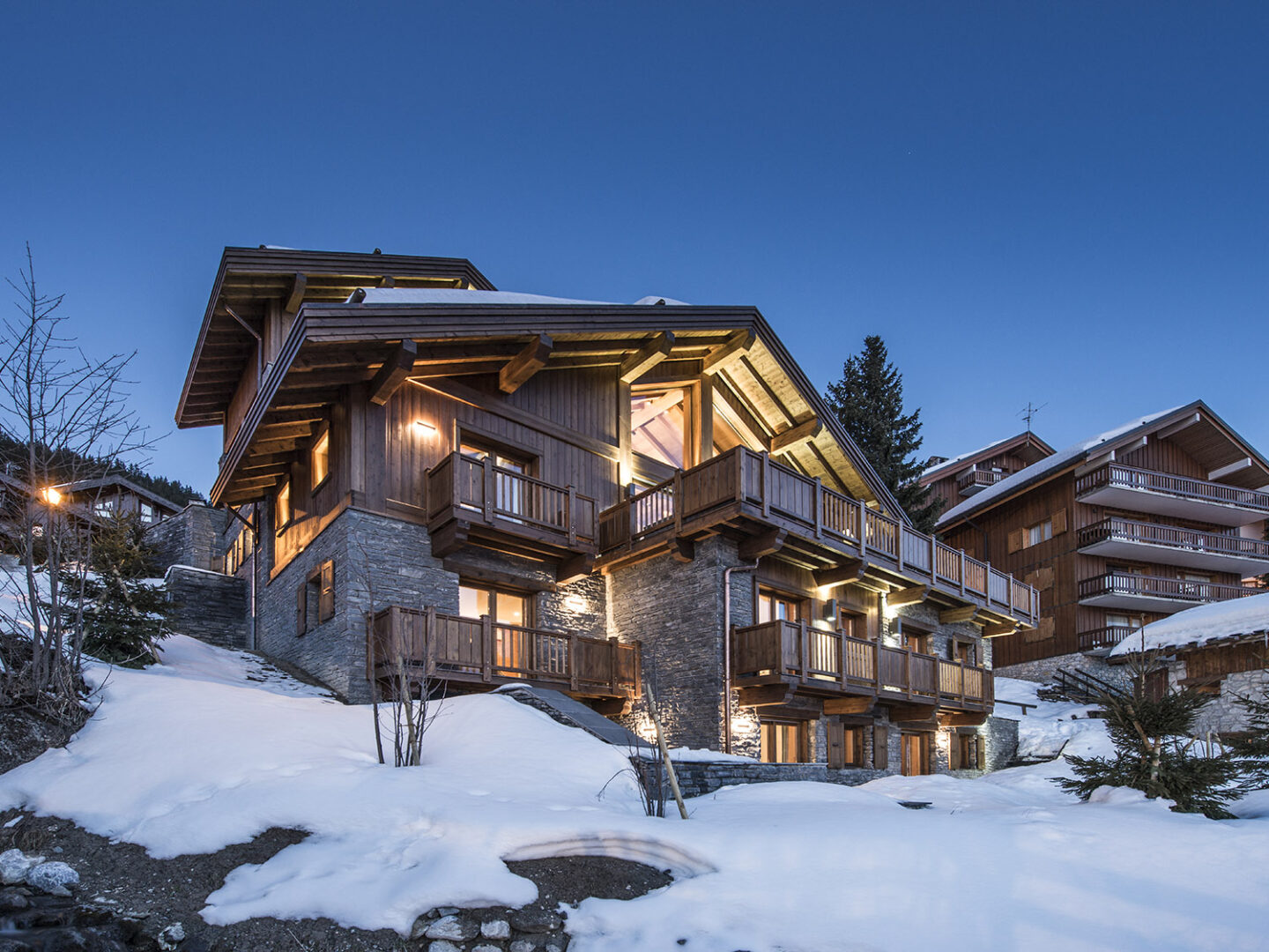 A snow-covered Chalet Le Grenier surrounded by a wintry landscape