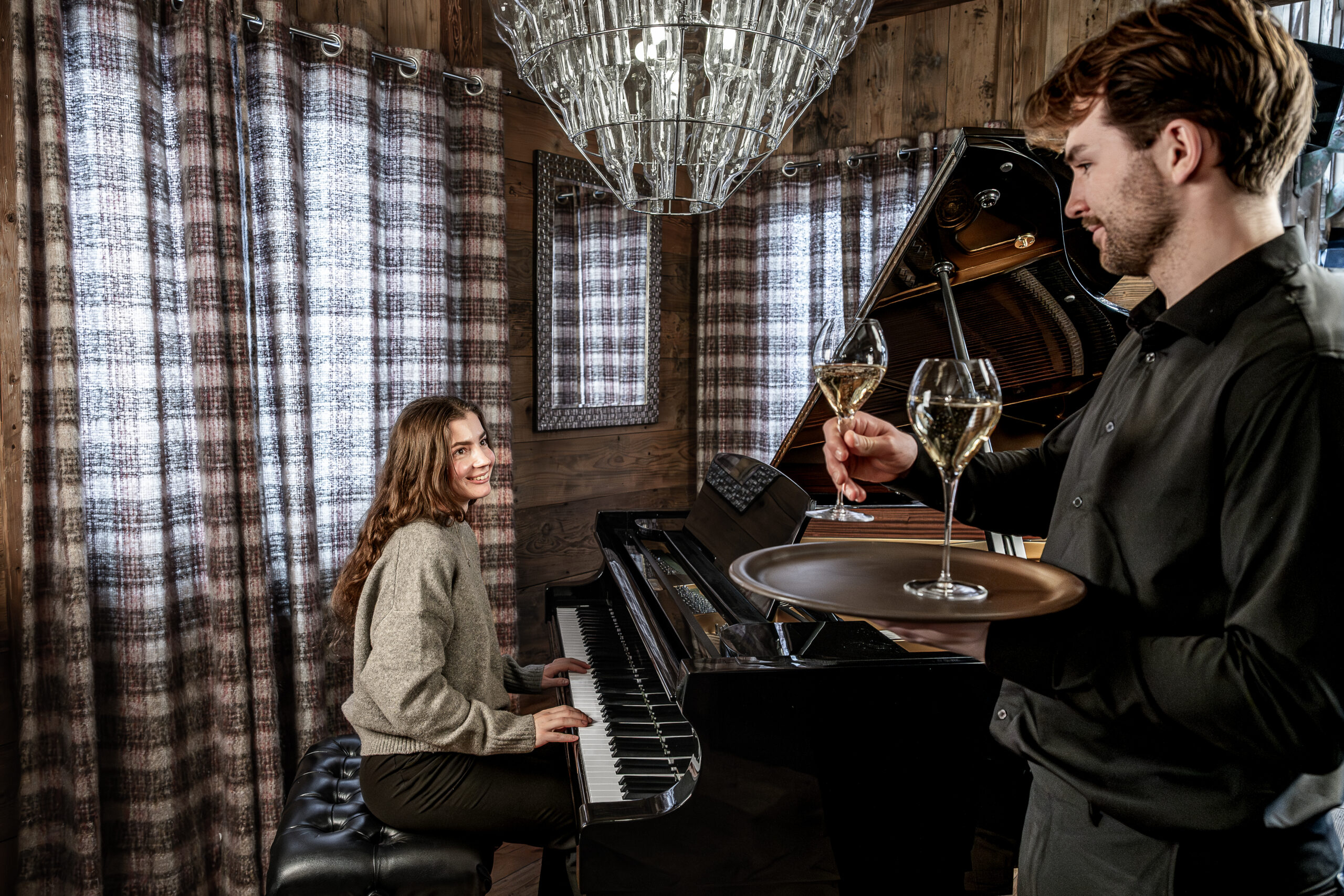 Chalet Le Rocher, women playing on the grand piano in living room with Champagne, French Alps